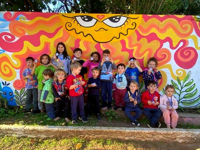 Turma reunida diante do mural do sol pintado no muro da Casa